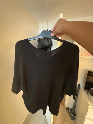 Svart v-ringad tröja med trekvartsarm - Enkel svart tröja med v-ringning och trekvartsärm. Tröjan har en loose passform och är tillverkad i ett mjukt, tunt material som känns skönt mot huden. Perfekt för lager på lager under höst och vår.