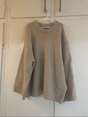 Beige stickad tröja från Lager 157 - Mysig beige stickad tröja från Lager 157 i oversized modell. Tröjan har rund halsringning, långa ärmar och ribbade muddar vid ärmslut och nederkant. Perfekt för lager på lager under kyliga dagar. För mig har den blivit lite kort i armarna och använder inte den längre. Pris kan disskuteras