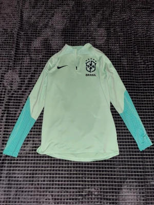 Nike Brasilien långärmad träningströja i grön - En grön Brasilien långärmad, ett perfekt alternativ för kallare dagar då man inte kan bära fotbolls T-shirts! Helt ny och oanvänd✅! Köpt och pris från Unisport för 879~ även slutsåld där. Mitt pris 600~💸 Tveka inte att höra av er vid minsta fundering! Priset går att diskutera vid snabb affär!⚡️