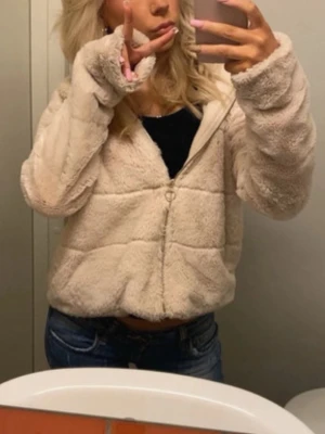 Beige teddyjacka med dragkedja - Skriv gärna för fler bilder❤️Mysig beige teddyjacka med dragkedja framtill och huva. Jackan är fluffig och har en avslappnad passform, perfekt för kyliga dagar. Långärmad och croppad modell som ger en trendig look. Passar till jeans eller mjukisbyxor.