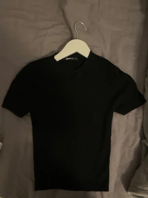 Svart stickad topp från Gina Tricot - En svart stickad topp från Gina Tricot i storlek XS. Toppen har korta ärmar och en klassisk rund halsringning. Enkel och stilren modell som är lätt att matcha till olika outfits.