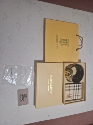 Rutig plånbok från Burberry - Säljer en snygg plånbok från Burberry med klassiskt rutigt mönster i beige, svart, vit och röd. Plånboken har Burberrys ikoniska ryttare tryckt på framsidan och är tillverkad i skinn. Perfekt för dig som gillar stilrena accessoarer med lyxig känsla.