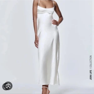 Vit långklänning i satin med öppen rygg - Supersnygg vit långklänning i satin från Zara. Klänningen har smala axelband, en elegant öppen rygg och en liten slits baktill. Den har en figurnära passform och stilren design som ger en lyxig känsla. Perfekt för dig som vill sticka ut med en minimalistisk look. (Klänningen är ny och har prislapp på.)