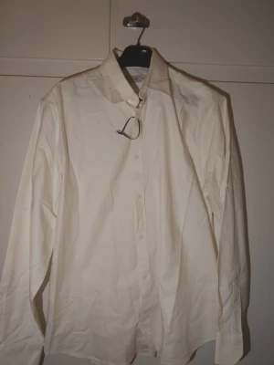 Klassisk vaniljvit skjorta från Sandö - Säljer en stilren vaniljvit skjorta från Sandö i storlek 50. Skjortan har klassisk krage, långa ärmar och knäppning framtill. Perfekt för dig som gillar en clean och enkel look. Tillverkad i bomull för en skön känsla hela dagen. ( Har en dålig kamera så bilderna blir lite knasiga).