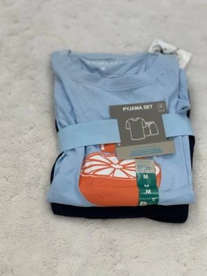Shorts and T-shirt - Bilderna visar ett pyjamasset med ljusblå t-shirt och mörkblå shorts från Primark, men ingen väst finns med.