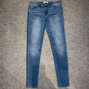 Levi's 511 blå skinny jeans - Snygga Levi's 511 jeans i klassisk blå tvätt med skinny passform. Jeansen har fem fickor, bälteshällor och dragkedja med knapp. Materialet är mjukt jeans och de har en modern, smal siluett som sitter tajt längs benen. Perfekt för dig som gillar en stilren look.