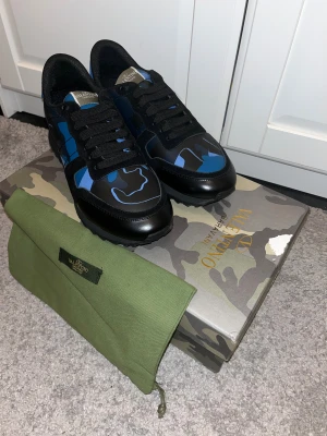 Valentino Rockrunner - Snygga Valentino Garavani Rockrunner sneakers i svart och blått med coolt camouflage-mönster. Skorna är i inprincip nyskick med minimalt slitage. Liten skada på boxen. Priset är inte hugget i sten och kan diskuteras. Allt på bilderna är det spm finns och ingår. 