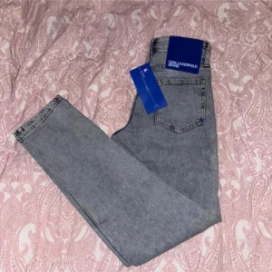 Blåa slim jeans från Karl Lagerfeld - Snygga grå jeans från Karl Lagerfeld Jeans i slim fit-modell. Jeansen har stretchigt denimtyg för extra komfort och sitter under midjan. Klassisk femficksdesign och diskret logga på bakfickan. Perfekta för en clean och stilren look.