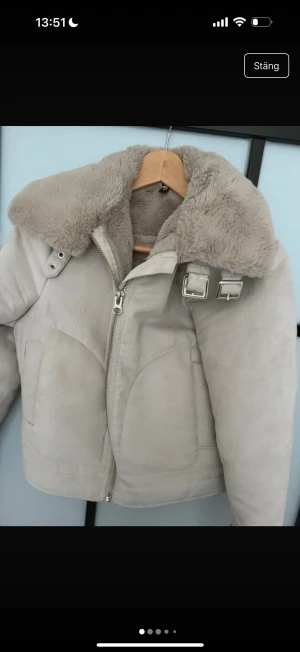 Beige teddyjacka med dragkedja - Säljer en mysig beige teddyjacka med dragkedja och fuskpälsfoder. Jackan har en hög krage med spänne och långa ärmar. Perfekt för kyliga dagar!