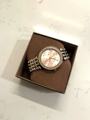 Michael Kors klocka - Snygg klocka från Michael Kors med roséguld och silverlänk. Klockan har stenar runt och stjärnor i mitten💘OBS! kommer ej med förpackningen!