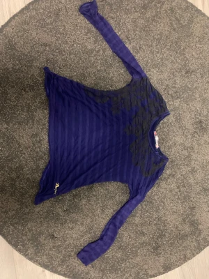 Blå långärmad topp från Desigual - Snygg blå långärmad topp från Desigual med svarta blommiga detaljer över axel och bröst. Tunt, randigt material som känns lätt och skönt mot huden. Rund halsringning och guldig broderad logga nertill. Perfekt för dig som gillar unika plagg med coola detaljer. Kortare i ryggen, nypris mellan 500-800. Knappt använd. Hör av dig vid frågor💕