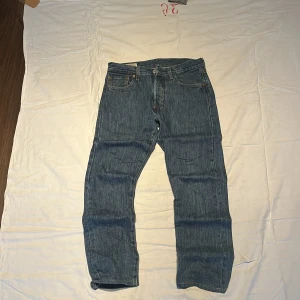 Levi's 501 Premium blå jeans W28 L32 - Säljer ett par klassiska Levi's 501 Premium jeans i blå denim. Modellen har rak passform, fem fickor och knappgylf. Snygga kontrastsömmar och ikonisk läderpatch baktill. Perfekt för dig som gillar tidlös stil och äkta denim.