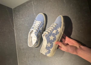 Saint Laurent jeans skor - Säljer ett par saint Laurent sneakers med jeans material. Skorna har vit snörning, lite gulaktig sula och detaljer i vitt skinn vid hälen. Ovandelen är i denimliknande tyg och de har en klassisk rund tå. Tillverkade i Spanien och perfekta för dig som vill sticka ut.