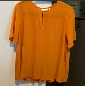 Blus från Inwear Stl S - Rost/orangefärgad blus från InWear med en liten öppning framtill och en knapp. Blusen har korta ärmar och ett plisserat parti nedtill i bak. Längd ca 60cm. Stl 36 