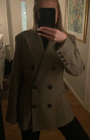 Rutig figursydd kavaj - Skitsnygg rutig kavaj ifrån HM med dubbelknäppning och knappar på ärmarna! Grå rutig.