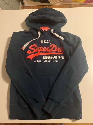 Superdry hoodie mörkgrön  - Superdry hoodie i mörkgrön färg. I helt perfekt skick som ny. Storlek S/M passar 171-181cm lång snygg och perfekt nu för vintern. Kolla även in mina andra annonser för mer snygga kläder och rabatt vid köp av flera 😃