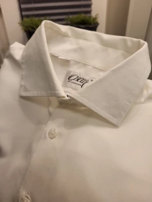 Vit skjorta Oscar of Sweden XL - Klassisk vit skjorta från Oscar of Sweden i strykfri bomull. Skjortan har lång ärm, bröstficka, knappar framtill och manschetter med två knappar. Perfekt för dig som gillar stilren och clean look.