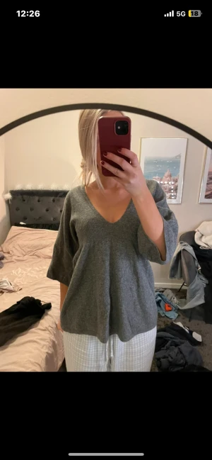 Grå v-ringad tröja Benetton - Mysig grå tröja från United Colors of Benetton med v-ringning och trekvartsärmar. Tröjan är i en loose passform och tillverkad i mjuk ull, perfekt för lager på lager under kyliga dagar.