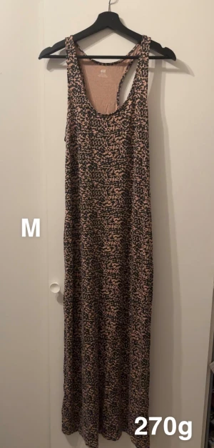 Leopardmönstrad långklänning H&M - Snygg långklänning från H&M med leopardmönster i svart och beige. Klänningen är ärmlös med breda axelband och har en avslappnad passform. Perfekt för dig som gillar djurmönster och vill ha en cool look.🌸Fint använt skick ( brun/beige i botten) storlek m