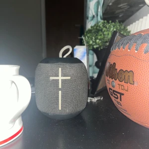 UE Wonderboom Bluetooth-högtalare -  Kraftfull och portabel UE Wonderboom Bluetooth-högtalare med tydligt ljud och djup bas. Vattentålig design, enkel att ta med tack vare smidig ögla. Några mindre repor och tecken på användning, men fungerar utmärkt. Perfekt för både inomhus och utomhusbruk. Svart färgad. DEN SER SMALL UT MEN DEN ÄR JÄTTEHÖG!!!