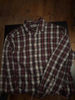 Rutig skjorta från TeX i XL - Rutig skjorta från TeX Casual Line i storlek XL. Skjortan har klassiskt rutmönster i svart, rött och vitt, med knappar framtill och lång ärm. Perfekt för en chill och avslappnad stil.