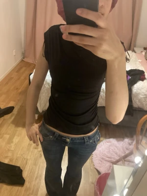 Svart ärmlös linnetopp med snörning - Säljer en svart, tight och ärmlös linnetopp med snörning vid axlarna. Toppen har en rund halsringning och är figurnära i modellen. Perfekt att styla med jeans eller kjol för en cool och enkel look.