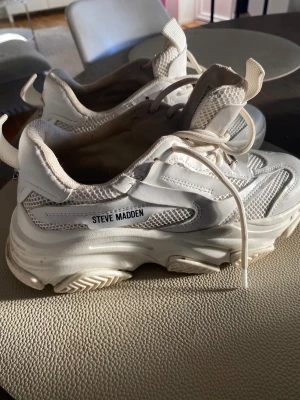Steve Madden vita chunky sneakers - Säljer ett par vita chunky sneakers från Steve Madden, modell Possession. Skorna har meshpaneler och detaljer i PU, samt snörning och grov platt sula. Märket syns på sidan och framtill. Perfekta för dig som gillar streetstyle och sportig vibe.