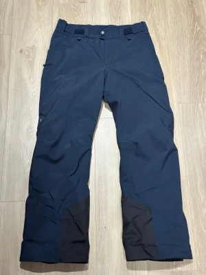 Peak Performance skidbyxor strl M - MAROON HIPE® 2L INSULATED SHELL PANTS HERR  Mångsidiga skidbyxor med stilren design och många smarta detaljer som snölås, fickor med dragkedja och heltejpade sömmar. Tillverkade av slittåligt, vind- och vattentätt HIPE®-tyg med utmärkt andningsförmåga. Håller dig bekväm och skyddad under aktiva friluftsäventyr. Vadderade skalbyxor i normal passform för pisten.  https://www.peakperformance.com/se/sv/product/m-maroon-insulated-pants-g80503.html?color=84178   Nypris 3000kr