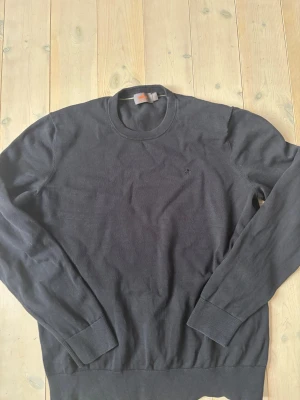 Morris tröja - Säljer en mörkblå långärmad tröja från Morris i storlek L, tillverkad i 100% pima bomull. Tröjan har rund hals och ett litet broderat emblem på bröstet. Perfekt för dig som gillar stilrena och klassiska plagg. Nypris 1399