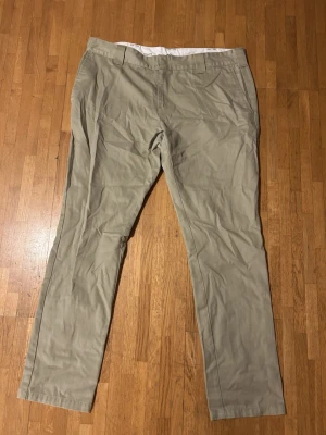 Beige Byxor från Dickies  - Säljer ett par klassiska beige chinos från Dickies i storlek W38/L34. Byxorna har raka ben, bälteshällor och fickor både fram och bak. Perfekt för dig som gillar enkel och clean stil. 