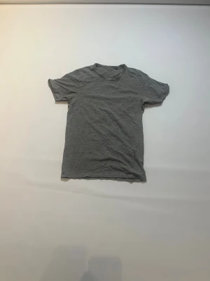 Grå t-shirt från Jack & Jones - En enkel grå t-shirt från Jack & Jones Essentials i storlek M. T-shirten har rund hals och korta ärmar, tillverkad i mjuk bomull som är skön mot huden. Perfekt för chill dagar och passar till det mesta i garderoben.