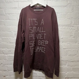 Oversize sweatshirt från Undercover - Cool brun sweatshirt från Undercover med trycket 'IT'S A SMALL PLANET SET DEEP IN SPACE' på framsidan. Tröjan har rund hals, långa ärmar, handvärmarfickor och är gjord i mjuk bomull. Perfekt för dig som gillar streetwear och unika prints. Storlek 4 (motsvarar XL)