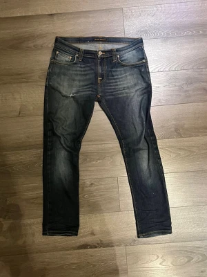 Nudie Jeans - Säljer dessa tvärfeta nudie jeansen med sjukt snygg fade och design, med en slitning också.  Passar perfekt till allt. De är W30 L32 dock lita kortare så skulle säga L31.