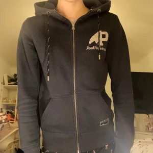 Snygg marinblå zip hoodie - Säljer en vintage Peak Performance zip hoodie med dragkedja😻Luvan har snören och dragkedjan får högt upp, perfekt när det är kallt! Hoodien har loggan tryckt på framsidan och en till detalj för extra snygghet🤍Den är väldigt mjuk och skön, superbra när man vill ha något snyggt men ändå mysigt. Passar till alla outfits! Hoodien har bra struktur❣️Storlek S, men passar XS också. Använd några gånger, inga synliga defekter💋