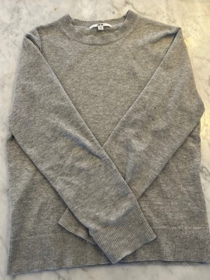 Grå Kashmir 100% - En enkel och stilren grå Kashmir tröja från Uniqlo i storlek XXS. Tröjan har rund hals, långa ärmar och ribbade muddar vid ärmslut och nederkant. Perfekt för lager-på-lager under kyliga dagar. Har en liten defekt som man ser på 3 bilden, Anars är tröjan i fint skick. Modelllen på bilden är lite över 160. Tveka inte att höra av er vid funderingar👕🔥