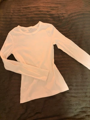 Vit ribbad långärmad topp Gina Tricot - Säljer en vit långärmad topp från Gina Tricot, basically basics-kollektionen. Toppen är ribbad och har en rund halsringning. Passformen är slim och materialet känns mjukt och stretchigt, perfekt att styla med jeans eller kjol. 