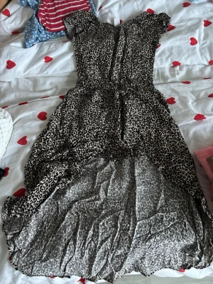 Leopardmönstrad långklänning från Lindex - Säljer en snygg långklänning från Lindex med leopardmönster i beige och svart. Klänningen har korta ärmar, markerad midja och ett luftigt, böljande tyg som ger en cool look. Perfekt för dig som gillar djurmönster och vill sticka ut.