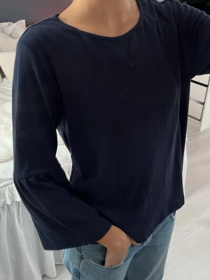 Mörkblå blus från Jacqueline de Yong - Säljer en stilren mörkblå blus från Jacqueline de Yong i storlek medium. Blusen har vida långärmar och en enkel rund halsringning. Materialet känns mjukt och lätt, perfekt att matcha med jeans eller kjol för en chill look.