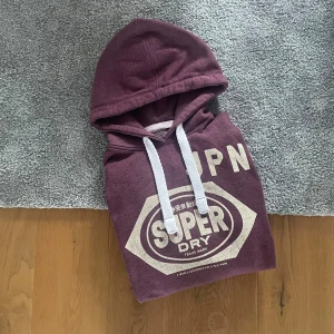 Vinröd Superdry hoodie - Hej! Säljer en jättefin vinröd Superdry hoodie i storleken L. Hoodien är i bra skick. Trycket är lite slitet men inte mer än så. Skriv vid minsta lilla fundering 