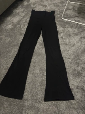 Svarta yogapants från Gina Tricot - Svarta bootcut byxor från Gina Tricot med hög midja (vikbara) och mjukt stretchigt material. Snyggt utsvängda ben och enkel design utan detaljer. Perfekta för dig som gillar en clean och bekväm look. Kan gå ner i pris🤗
