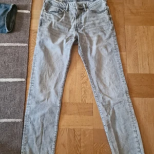 Grå straight jeans från H&M - Snygga grå jeans från H&M med straight passform och regular fit. Klassisk femficksmodell med bälteshällor och knappgylf. Jeansen har en ljusgrå tvätt och raka ben, perfekta för en clean och avslappnad look.