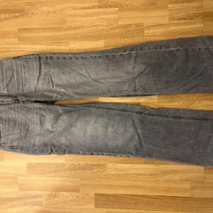 Grå jeans från Stradivarius, storlek 34 - Säljer ett par grå tvättade jeans från Stradivarius i storlek 34. Jeansen har klassisk femficksdesign, raka ben och normal passform. Perfekta till sneakers eller boots och funkar året runt. Materialet är mjukt och stretchigt för extra komfort.