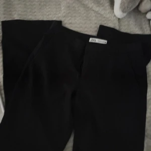 Svarta kostymbyxor från Zara - Svarta kostymbyxor från Zara med klassisk rak passform. Byxorna har diskreta sidfickor och är perfekta för en clean och stilren look. Materialet känns mjukt och följsamt, vilket gör dem bekväma att bära hela dagen.