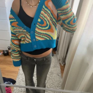 Färgglad kofta från Stradivarius XS - Säljer en supercool cardigan /kofta från Stradivarius i storlek XS. Koftan har ett färgstarkt mönster i blått, orange, gult och rosa med bred ribbad kant och knappar framtill. Coola färger, lite tecken på användning annars mycket bra 