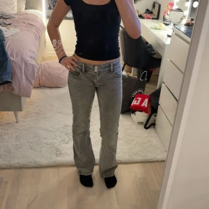 Grå bootcut jeans med stjärna - Snygga grå jeans med bootcut passform och låg midja. Jeansen har en cool stjärndetalj på bakfickan och klassiska fem fickor. Storlek 164 från Gina young 