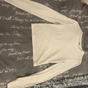 Vit långärmad ribbad tröja - En enkel vit långärmad tröja med diskret ribbad struktur. Tröjan har rund halsringning. I storlek S