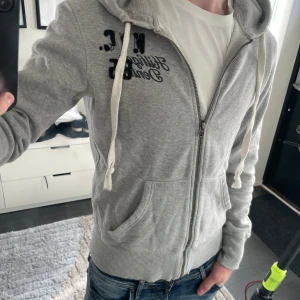 Grå zip hoodie från Hilfiger Denim - Säljer en grå zip hoodie från Hilfiger denim i storlek S. Modellen är ca 180cm. Hör av dig vid funderingar!