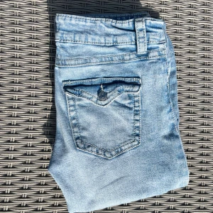 Ljusblå bootcut jeans från Gina Tricot - Säljer ett par ljusblå jeans från Gina Tricot med låg midja och bootcut-ben. Jeansen har klassiska fickor fram och bak, varav bakfickorna har lock och knapp. Har stl 164 men passar upp till S🩵