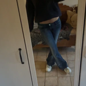 Blå bootcut jeans låg midja - Säljer ett par blå jeans med bootcut-modell och låg midja. Jeansen har klassisk femficksdesign, lätt slitning på låren och är i ett mjukt denimtyg. Perfekta för dig som gillar en avslappnad och trendig look.