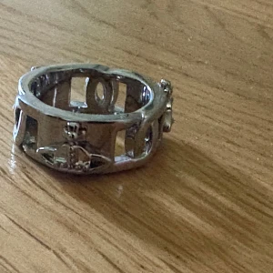 Vivienne Westwood Orb ring silver - Cool bred ring i silverfärgad metall från Vivienne Westwood med det ikoniska Orb-emblemet runt om. Har kvitto